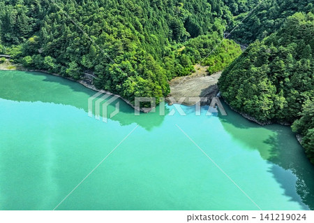 An aerial photograph overlooking the jade-colored surface of Lake Ikawa in Shizuoka Prefecture and the surrounding green forest. An aerial photograph overlooking the jade-colored surface of Lake Ikawa in Shizuoka Prefecture and the surrounding green forest. 141219024
