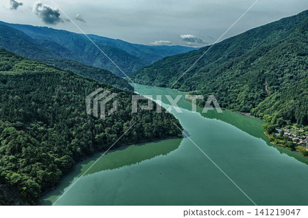 An aerial photograph showing Lake Ikawa and the surrounding green mountains in Shizuoka Prefecture from a diagonal vantage point. 141219047