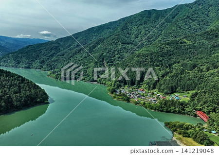 An aerial photograph overlooking Lake Ikawa, a red bridge, and a mountain village in Shizuoka Prefecture. An aerial photograph overlooking Lake Ikawa, a red bridge, and a mountain village in Shizuoka Prefecture. 141219048