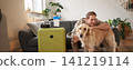 Portrait of happy young man going on holiday, travelling with his dog companion, sitting with golden retriever near suitcases and tickets 141219114
