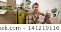 Portrait of smiling handsome tourist, man holding passport and flight tickets, sitting with suitcase 141219116