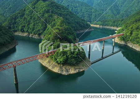 An aerial photograph overlooking Oku-Oi Lake Station in Shizuoka Prefecture and the red railway bridge spanning Lake Sessoko. 141219120