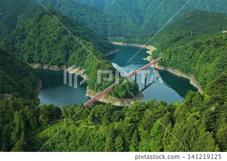 An aerial photograph overlooking Lake Sessoko and the red railway bridge at Oku-Oi Lake Station in Shizuoka Prefecture. An aerial photograph overlooking Lake Sessoko and the red railway bridge at Oku-Oi Lake Station in Shizuoka Prefecture. 141219125
