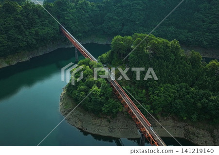 An aerial photograph overlooking Oku-Oi Lake Station and the red railway bridge spanning Lake Sessoko. An aerial photograph overlooking Oku-Oi Lake Station and the red railway bridge spanning Lake Sessoko. 141219140