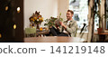Portrait of happy, relaxed young man sitting in cafe alone, wearing wireless headphones, playing video game on tablet, laughing and smiling, looking at his device. Concept of lifestyle and people 141219148