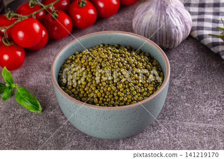Bowl of green mung beans with cherry tomatoes and garlic on rustic surface 141219170