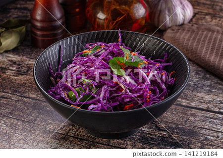 Vibrant purple cabbage salad in black bowl on rustic wooden table Vibrant purple cabbage salad in black bowl on rustic wooden table 141219184