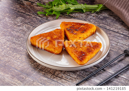 Crispy golden fried triangular food pieces on white plate with arugula 141219185