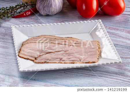 Sliced pastrami on white plate with garlic tomatoes and herbs 141219199