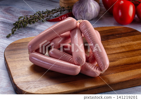Raw sausages on wooden cutting board with garlic and tomatoes Raw sausages on wooden cutting board with garlic and tomatoes 141219201