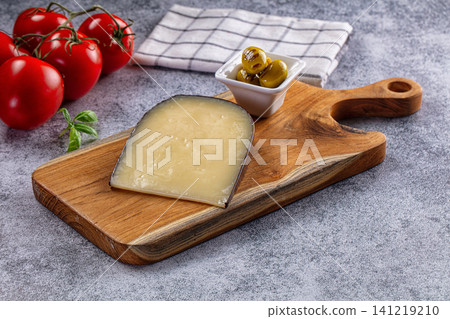Cheese wedge on wooden board with tomatoes and olives 141219210
