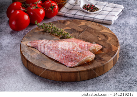 Raw sea perch fillet on wooden cutting board with tomatoes and thyme 141219212