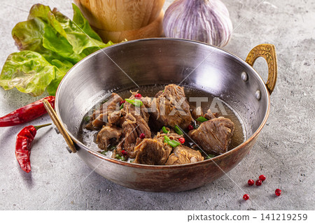 Stewed lamb in metal bowl with red chili peppers and garlic Stewed lamb in metal bowl with red chili peppers and garlic 141219259