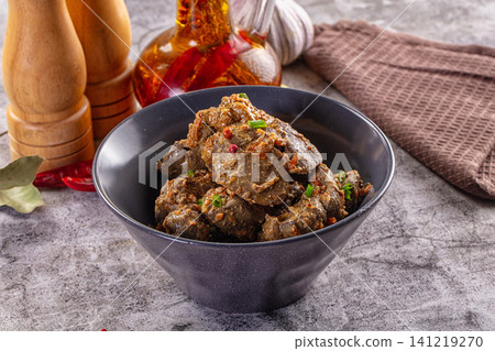 Spiced liver dish in black bowl with garlic and chili Spiced liver dish in black bowl with garlic and chili 141219270