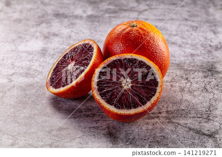 Blood orange halves and whole fruit on textured gray surface 141219271