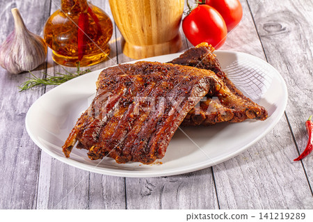 Grilled pork ribs on white plate with garlic chili oil and tomatoes Grilled pork ribs on white plate with garlic chili oil and tomatoes 141219289