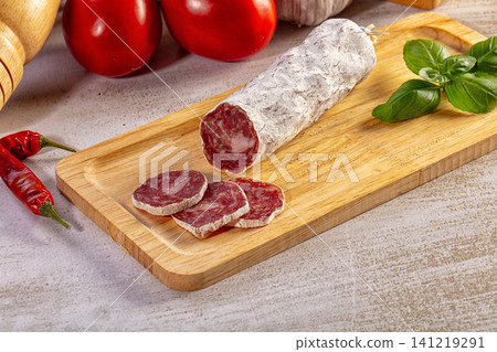 Dry cured salami sausage sliced on a wooden board with tomatoes, basil, and garlic Dry cured salami sausage sliced on a wooden board with tomatoes, basil, and garlic 141219291