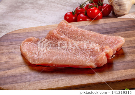 Raw chicken breast on wooden cutting board with cherry tomatoes and garlic 141219315