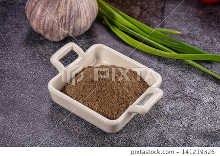 Ground black pepper in ceramic dish with garlic and green onions on dark textured surface Ground black pepper in ceramic dish with garlic and green onions on dark textured surface 141219326
