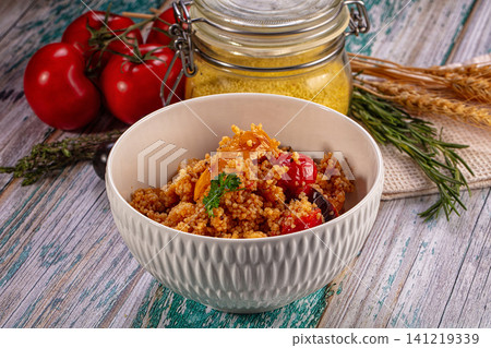 Couscous salad with roasted tomatoes and herbs in ceramic bowl on rustic wood Couscous salad with roasted tomatoes and herbs in ceramic bowl on rustic wood 141219339