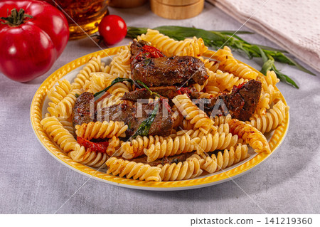 Pasta with grilled meat and herbs on yellow plate 141219360