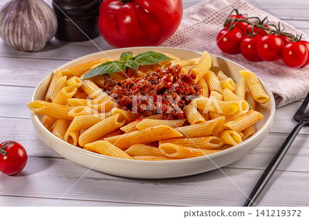 Penne pasta with bolognese sauce and fresh basil on wooden table Penne pasta with bolognese sauce and fresh basil on wooden table 141219372