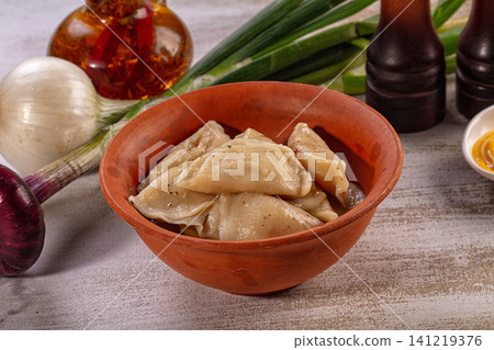 Vareniki dumplings in terracotta bowl with fresh vegetables and condiments Vareniki dumplings in terracotta bowl with fresh vegetables and condiments 141219376
