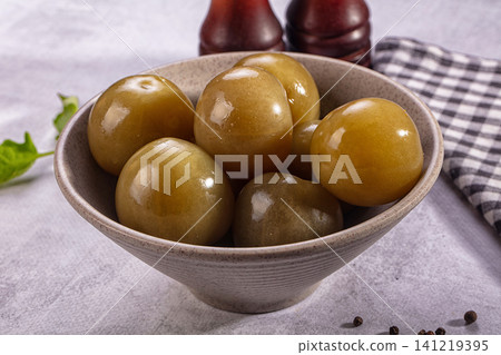 Green olives in ceramic bowl with checkered napkin and pepper mills Green olives in ceramic bowl with checkered napkin and pepper mills 141219395