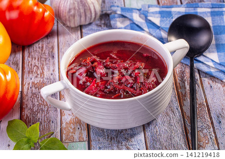 Borsch soup in white bowl with red peppers and garlic on rustic wooden table Borsch soup in white bowl with red peppers and garlic on rustic wooden table 141219418