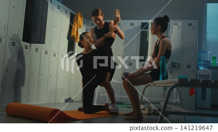 Professional Young Gymnast Performing Vertical Leg Split with Friends Assistance Professional Young Gymnast Performing Vertical Leg Split with Friends Assistance 141219647