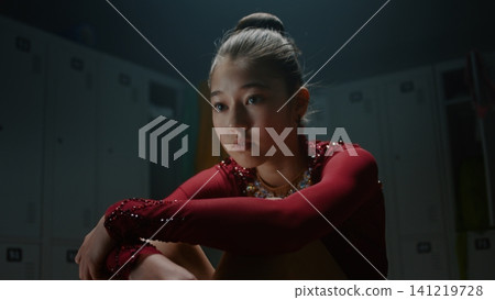 Anxious Teen Gymnast in Shiny Competition Leotard Sitting Alone Backstage Anxious Teen Gymnast in Shiny Competition Leotard Sitting Alone Backstage 141219728