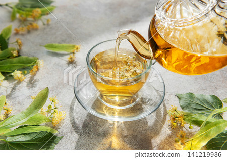 Pouring linden tea into glass cup for relaxation Pouring linden tea into glass cup for relaxation 141219986