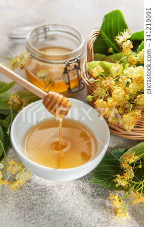 Honey dripping into bowl with linden flowers Honey dripping into bowl with linden flowers 141219991