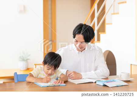 A young boy and his father studying in the living room. A young boy and his father studying in the living room. 141220725