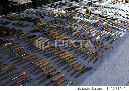 XALO, SPAIN - JUNE 20, 2026.Collectors browse through a wide selection of pocket knives and folding knives with wooden handles arranged on a blue tablecloth at a market. The atmosphere is busy with tr XALO, SPAIN - JUNE 20, 2026.Collectors browse through a wide selection of pocket knives and folding knives with wooden handles arranged on a blue tablecloth at a market. The atmosphere is busy with tr 141221041