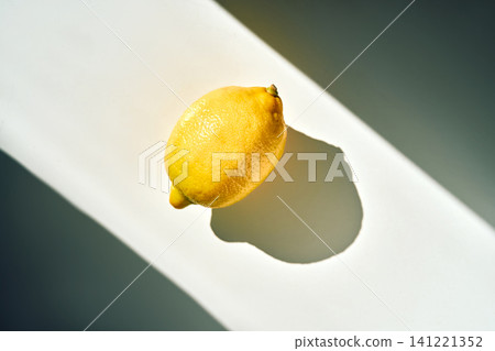 Bright yellow lemon casting long shadow under natural light Bright yellow lemon casting long shadow under natural light 141221352