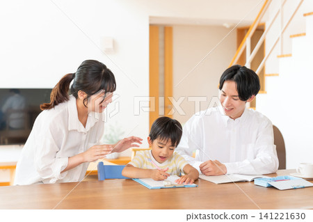 A boy studying at the living room table, watched over by his parents. A boy studying at the living room table, watched over by his parents. 141221630