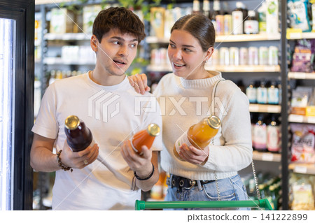 Couple man and woman choosing juices in grocery Couple man and woman choosing juices in grocery 141222899