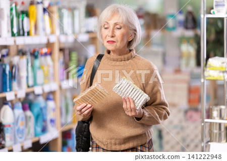 Mature woman choosing clothes pegs in department store Mature woman choosing clothes pegs in department store 141222948