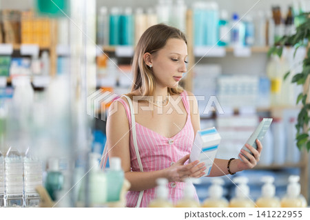 Woman in dress choosing cream in pharmacy Woman in dress choosing cream in pharmacy 141222955