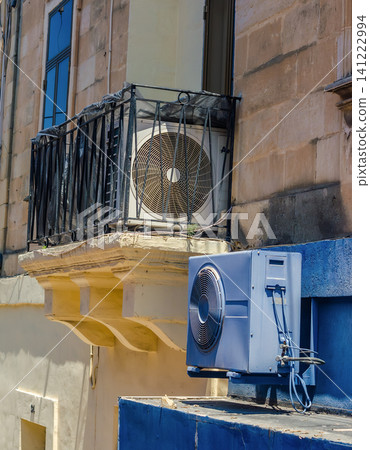 Modern air conditioning outdoor units mounted on a traditional stone balcony and blue wall in a Mediterranean city. High quality photo Modern air conditioning outdoor units mounted on a traditional stone balcony and blue wall in a Mediterranean city. High quality photo 141222994