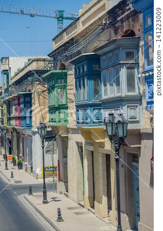 Colorful traditional Maltese enclosed wooden balconies on limestone townhouses along a quiet street in Malta with vintage lampposts. High quality photo Colorful traditional Maltese enclosed wooden balconies on limestone townhouses along a quiet street in Malta with vintage lampposts. High quality photo 141223009