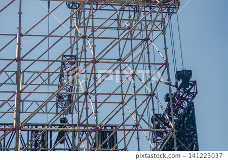 Detail of metal scaffolding and truss rigging with suspended speakers and lighting for an outdoor concert stage against a blue sky. High quality photo Detail of metal scaffolding and truss rigging with suspended speakers and lighting for an outdoor concert stage against a blue sky. High quality photo 141223037