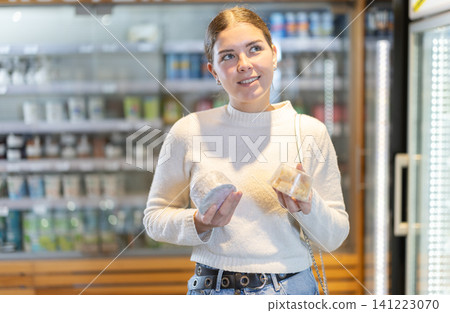 Woman choosing cheese in a store Woman choosing cheese in a store 141223070
