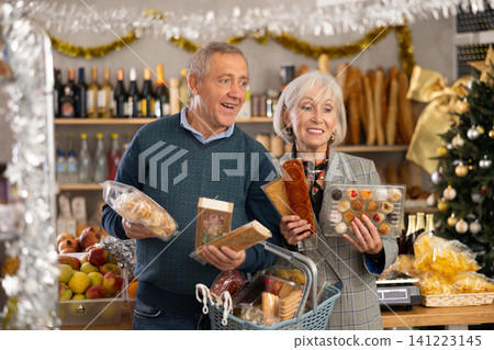 Elderly couple choose from several deserts, consider nougat, panellets, marzipan Elderly couple choose from several deserts, consider nougat, panellets, marzipan 141223145