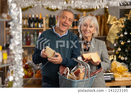 Elderly couple is looking at cheese in store on eve of New Year holidays Elderly couple is looking at cheese in store on eve of New Year holidays 141223195