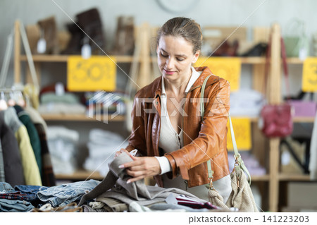European woman customer examine and choose trousers in store 141223203