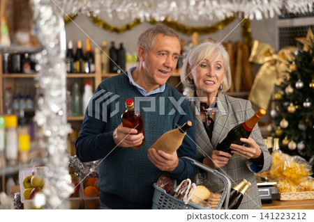 Mature husband and wife choosing wine and whiskey for Christmas celebration at supermarket 141223212