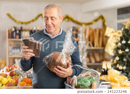 Elderly man chooses chocolates and panettone at grocery Elderly man chooses chocolates and panettone at grocery 141223246