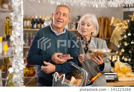 Visiting store on New Years Eve, senior spouses is looking at something on shelf of showcase. Visiting store on New Years Eve, senior spouses is looking at something on shelf of showcase. 141223268